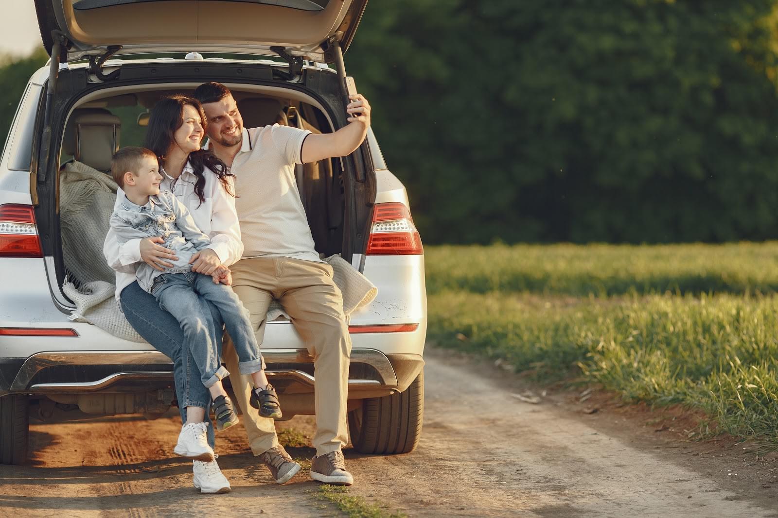 Family taking photo in open trunk of car